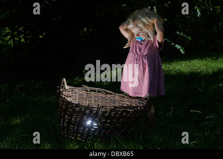 Bambino ragazza bionda ha trovato un tesoro nel cesto di vimini Foto Stock