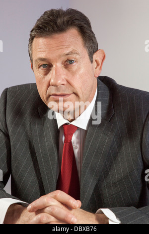 Ritratto di un uomo d affari a una scrivania, guardando la telecamera, vicino. Foto Stock