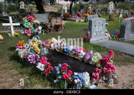 McAllen, Texas - fiori artificiali e acqua in bottiglia in una tomba a La Piedad cimitero. Foto Stock