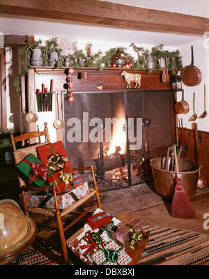 Dagli anni sessanta del tempo antico camino decorato per il Natale con regali impacchettati Foto Stock