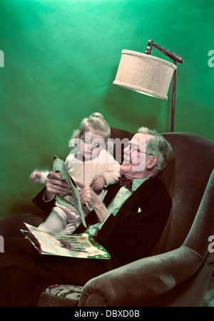 Negli anni quaranta anni cinquanta nipote seduta sul sorridente NONNO GIRO LA LETTURA DI LIBRI DI IMMAGINI Foto Stock