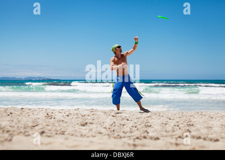 Attraente uomo giocando frisby sulla spiaggia in estate sport fitness jump Foto Stock