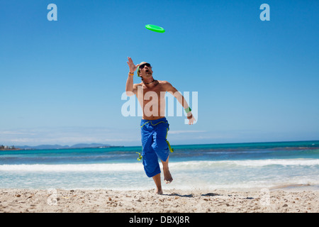 Attraente uomo giocando frisby sulla spiaggia in estate sport fitness jump Foto Stock