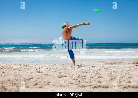 Attraente uomo giocando frisby sulla spiaggia in estate sport fitness jump Foto Stock