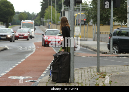 Una donna con una custodia da viaggio attende per un taxi in Donnybrook, a sud di Dublino durante uno sciopero da Dublin Bus Foto Stock