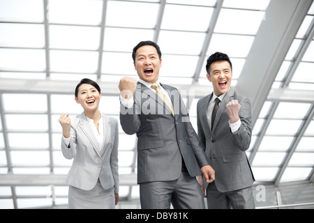 Eccitata la gente di affari che celebra nella lobby di airport Foto Stock