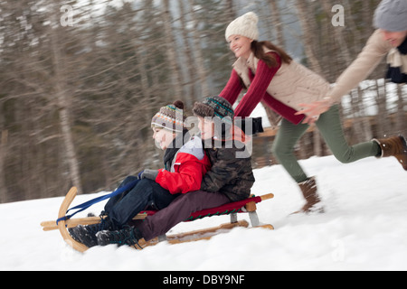 Famiglia entusiasta slittino nel campo nevoso Foto Stock