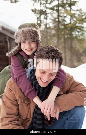 Ritratto di felice figlio abbraccia il padre nella neve Foto Stock