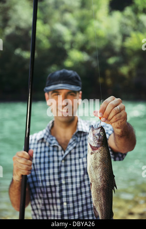 Metà adulto pescatore per vacanze sul fiume, rilassante e la pesca alla trota. Focus sui pesci Foto Stock