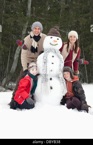 Ritratto di famiglia felice con pupazzo di neve Foto Stock