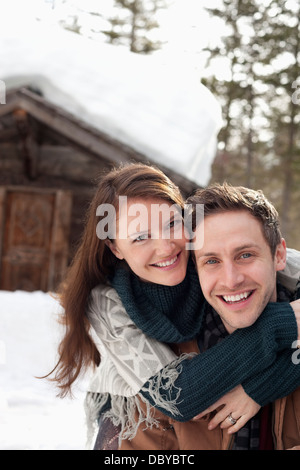 Ritratto di coppia felice costeggiata in snow esterno cabina Foto Stock