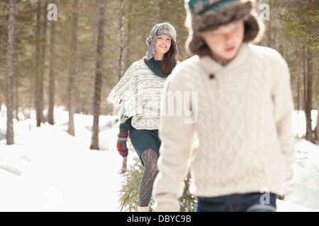 Madre e figlio fresco di trascinamento albero di Natale in boschi innevati Foto Stock