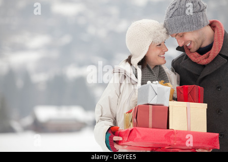 Felice coppia portando regali di Natale nella neve Foto Stock