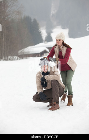 Coppia felice godendo lotta con le palle di neve nel campo Foto Stock