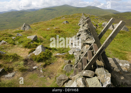Montante della scala a secco su muro di pietra al vertice di Tal-y-Ventola con Foel Fras all'orizzonte, Gwynedd, Snowdonia, il Galles del Nord. Foto Stock
