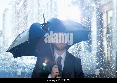 Frustrati imprenditore con rotture di ombrello in caso di pioggia Foto Stock