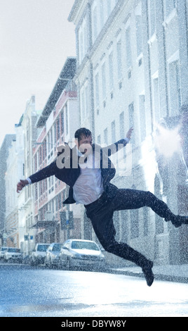 Imprenditore dancing in rainy street Foto Stock