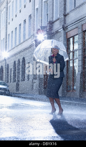 Imprenditrice sotto ombrellone in rainy street Foto Stock