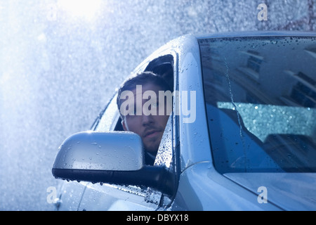 Imprenditore in auto a guardare fuori dalla finestra a pioggia Foto Stock