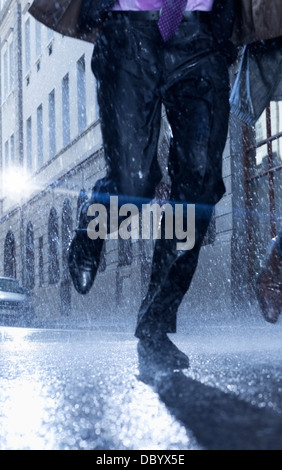 Imprenditore in esecuzione in rainy street Foto Stock