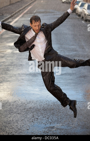 Imprenditore entusiasta dancing in rainy street Foto Stock