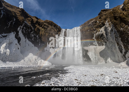 Congelati cascata Skogafoss con arcobaleno, Islanda. Foto Stock