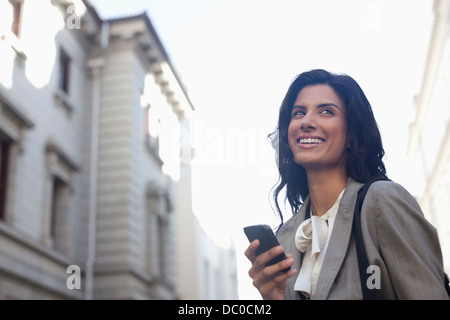 Felice imprenditrice la messaggistica di testo con un telefono cellulare Foto Stock