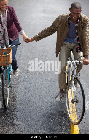 Coppia felice tenendo le mani e di andare in bicicletta Foto Stock