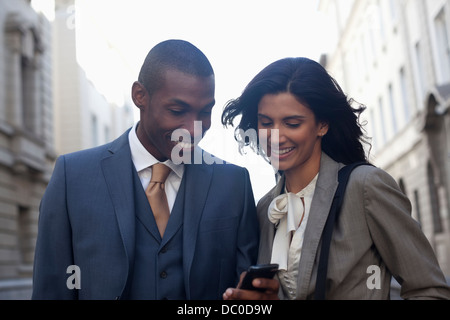 Sorridente la gente di affari per la messaggistica di testo con un telefono cellulare Foto Stock