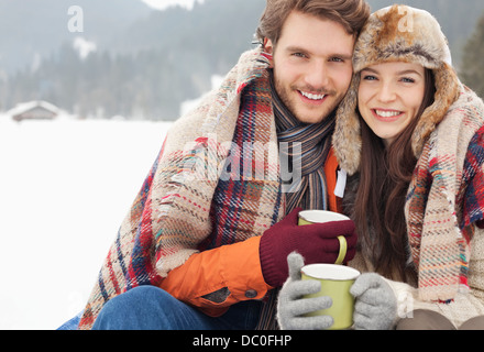 Ritratto di coppia felice di bere il caffè in campo nevoso Foto Stock