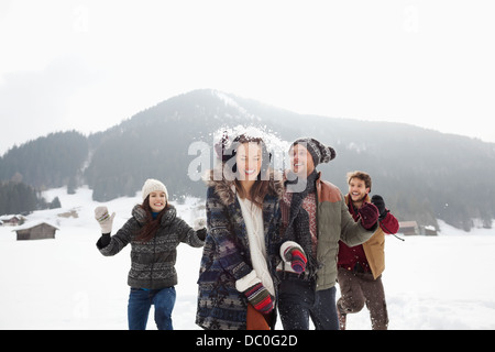 Giocoso amici godendo lotta con le palle di neve nel campo Foto Stock