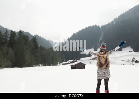 Carefree donna con le braccia aperte in campo nevoso Foto Stock