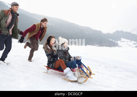 Amici entusiasti slittino nel campo nevoso Foto Stock