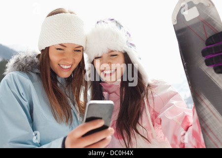 Le donne con gli sci per la messaggistica di testo con un telefono cellulare Foto Stock