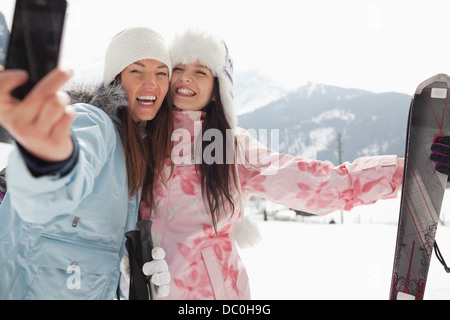Donne entusiasta con sci tenendo autoritratto con la fotocamera del telefono nel campo Foto Stock