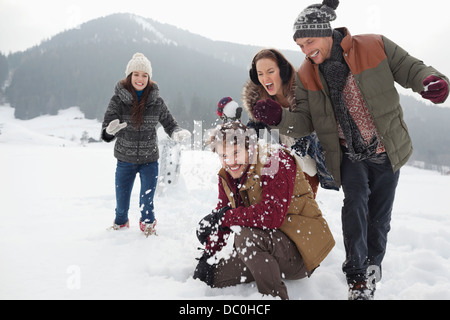 Giocoso amici godendo lotta con le palle di neve nel campo Foto Stock