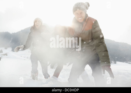 Ritratto di giocosi amici godendo lotta con le palle di neve nel campo Foto Stock