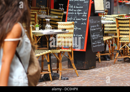 Ragazza passando da un cafe a rue Mouffetard - tradizionale arredamento in vimini e schede di menu esposti sul marciapiede, Parigi, Francia Foto Stock