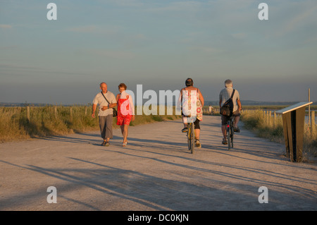 Camminatori e ciclisti nella calda luce della sera vicino alla baia di Le Crotoy cittadina nel dipartimento della Somme in Picardie nella Francia del nord Europa. Foto Stock