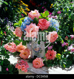 BOUQUET di rose rosa e blu ortensie in vaso sulla panchina da giardino Foto Stock