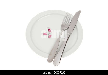 Pillole con un coltello e forchetta su una piastra isolata contro bianco Foto Stock