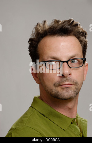 Un uomo con gli occhiali, una verde Polo shirt e barba lunga Foto Stock