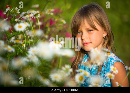 Poco bella ragazza outdoor tra i fiori di campo Foto Stock