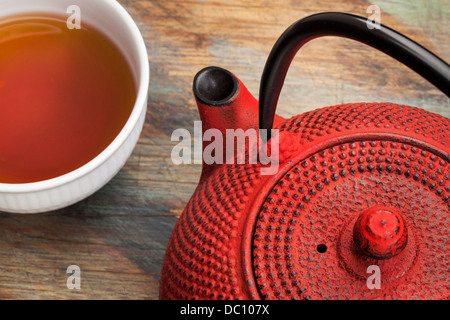 Tetsubin rosso con una tazza di tè - un dettaglio di un tradizionale ghisa teiera giapponese Foto Stock