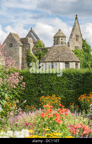 Colombaia in pietra e la facciata in rovina a Nymans, Haywards Heath, West Sussex, in Inghilterra con bordo colorato di fiori d'estate Foto Stock