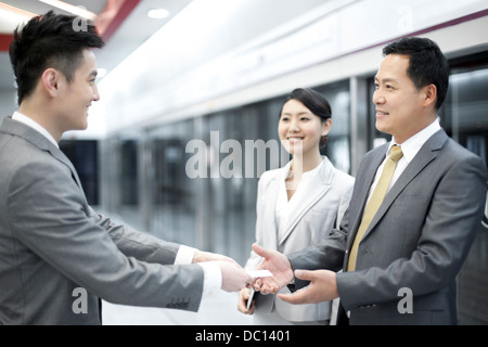 Imprenditore consegna business card per nuovi amici sulla piattaforma della metropolitana Foto Stock