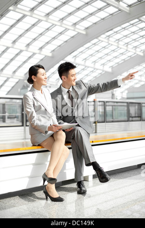 Colleghi di lavoro cercando di visualizzare alla stazione della metropolitana Foto Stock