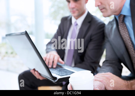 Imprenditori a bere caffè e la condivisione di computer portatile Foto Stock