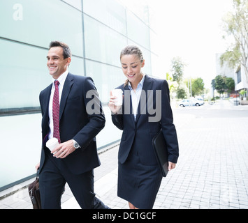 Imprenditore sorridente e imprenditrice a piedi con il caffè Foto Stock