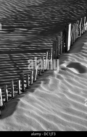 Recinzione in legno in dune di sabbia con forti ombre dalla luce solare Foto Stock